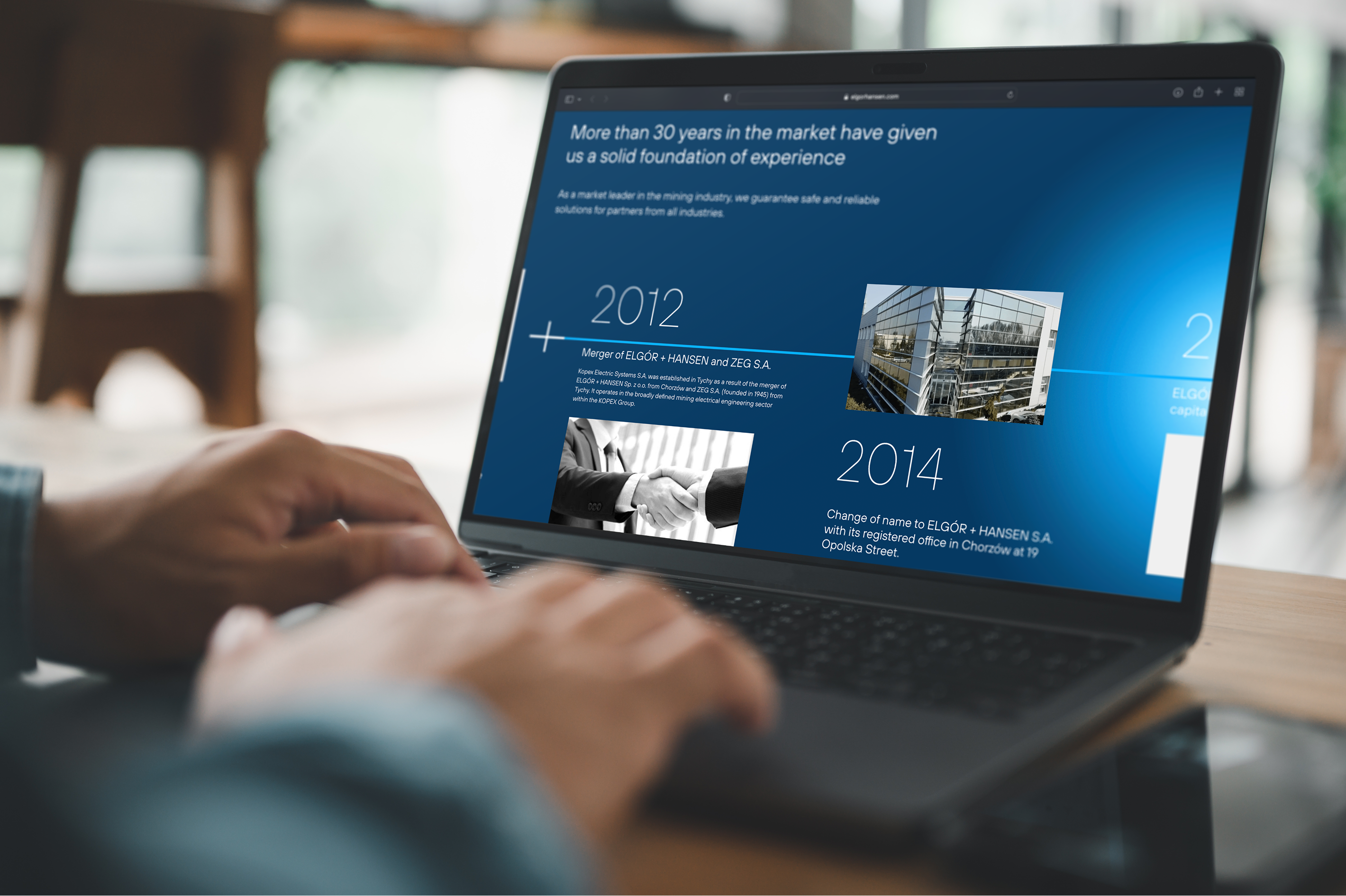 A person types on a laptop displaying a user-friendly company timeline with milestones from 2012 and 2014, featuring text, photos, and a blue background. The modern, bright workspace enhances the WordPress-powered presentation.