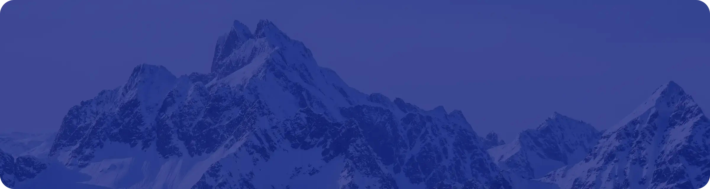 Snow-covered mountain peaks rise sharply against a clear blue sky, creating a dramatic and rugged landscape. The scene is shaded with a blue tint, enhancing the cold and serene atmosphere.