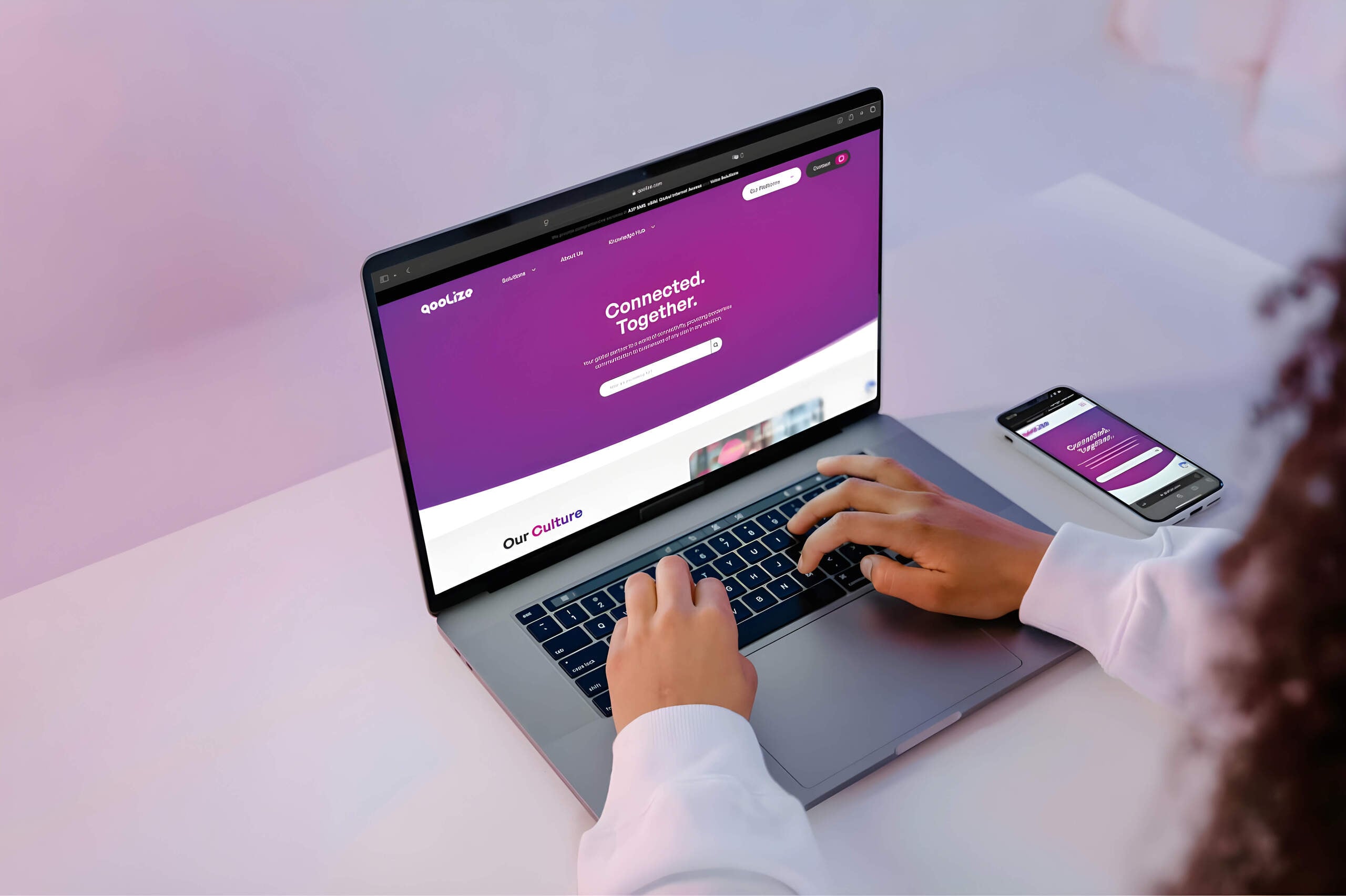 A person types on a laptop displaying a purple website with the text “Connected. Together.” A smartphone beside the laptop shows the same site—perfect for showcasing a wordpress development agency's modern, cohesive design.