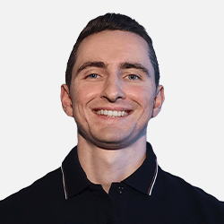 A young man with short brown hair smiles at the camera, wearing a black collared shirt against a plain, light-colored background—perfect for an Osom Studio website or WordPress profile photo.
